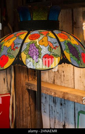 Tiffany lamp with recurring fruit patterns inside old rustic wood plank cabin. Stock Photo