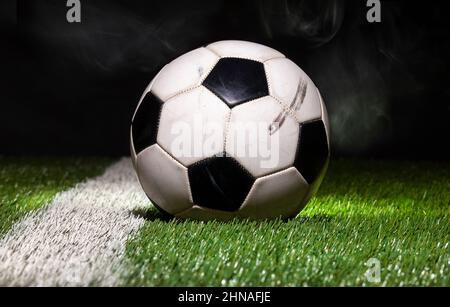 Low angle view of soccer ball on grass field with dark background and smoke Stock Photo
