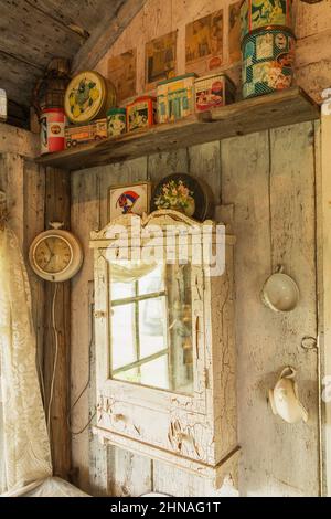 Antique medicine cabinet on wall and metal Coca Cola cans on shelf inside old rustic wood plank cabin. Stock Photo