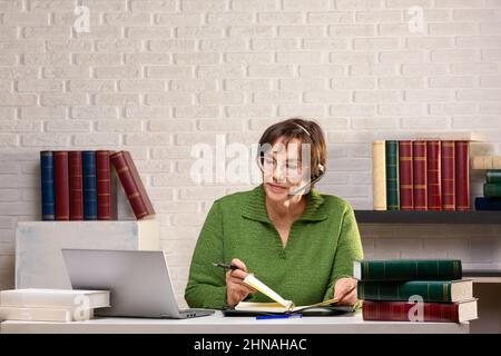 Woman senior adult works in front of a laptop monitor in office. Format phtot 2x1. Stock Photo