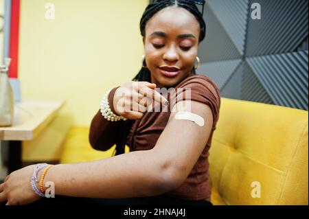 Stay safe! Black woman showing vaccinated arm after vaccine injection. Stock Photo