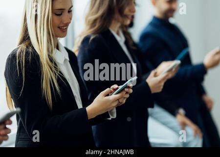 Portrait diverse candidates sitting on chairs in row, looking at camera, business people applicants interns waiting for job interview, holding gadgets Stock Photo