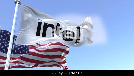 San Francisco, CA, USA, February 2022: The flag of Intel Corporation waving in the wind with the national flag of the United States of America. Stock Photo