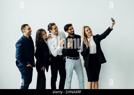 Happy diverse colleagues have fun make self-portrait picture on cellphone together. Smiling young multiracial businesspeople pose for selfie on smartp Stock Photo