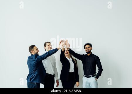 Happy multinational colleagues diverse business people standing in modern office giving high five holding hands together celebrating great results in Stock Photo