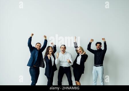 Cheerful active multiracial colleagues dancing enjoy corporate party or celebrating successful deal success at work common project feels happy have fu Stock Photo