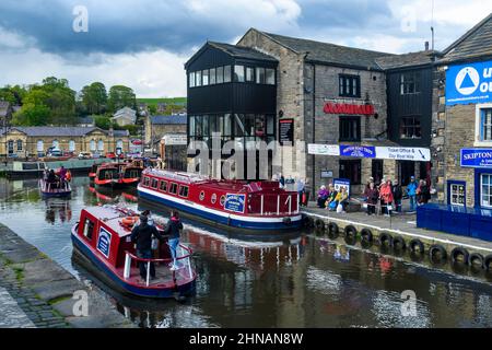 Tourist leisure trip on water (men women, self-drive red hire boat, customers queuing, moorings) - scenic Leeds-Liverpool Canal, Yorkshire, England UK Stock Photo