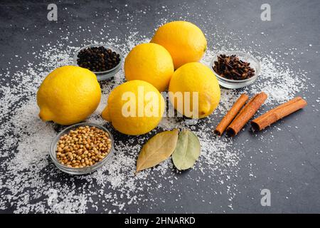 Ingredients Used to Make Preserved Lemons: Fresh lemons, whole spices, and kosher salt on a dark background Stock Photo