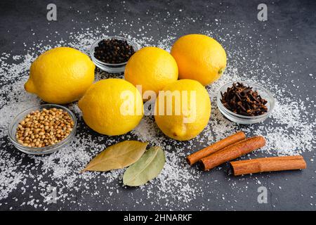 Ingredients Used to Make Preserved Lemons: Fresh lemons, whole spices, and kosher salt on a dark background Stock Photo