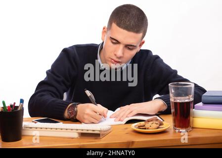 young men writing in a book and working in the computer at home, online school Stock Photo