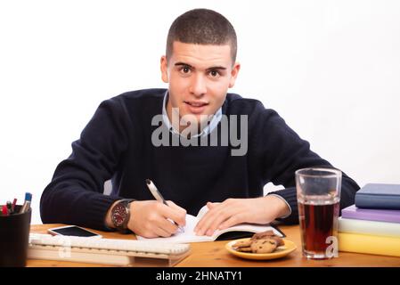 young men writing in a book and working in the computer at home, online school Stock Photo