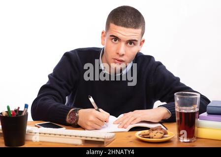 young men writing in a book and working in the computer at home, online school Stock Photo