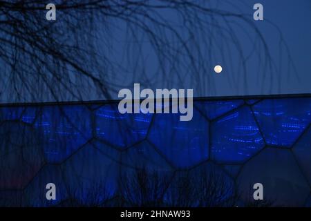 Beijing, China. 15th Feb, 2022. Photo taken on Feb. 15, 2022 shows the moon and the National Aquatics Centre in Beijing, capital of China, Feb. 15, 2022. Credit: Huang Xiaobang/Xinhua/Alamy Live News Stock Photo