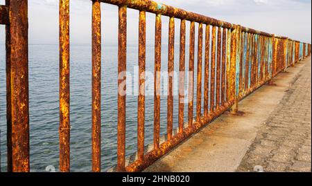 Rusty iron railing, beautiful sea and sky landscape view between oxidized railing gap. Stock Photo