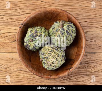 Sugar apples or custard apples in a bowl over wooden table. Stock Photo