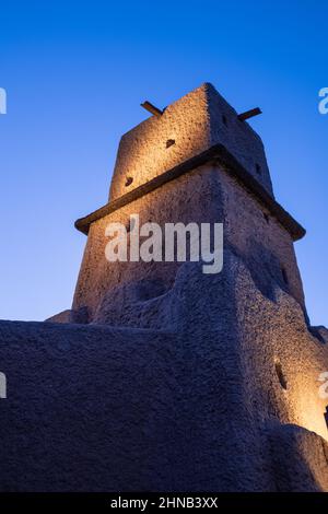 Rock and stone squared tall tower on a blue night sky lightened by yellow lights Stock Photo