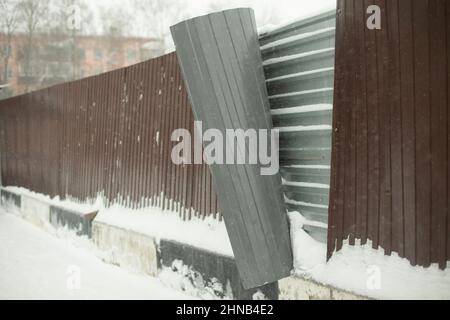 Broken fence. Steel fence buckled away from gusts of wind. Territory is fenced. Damage to stainless professional sheet. Stock Photo