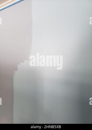 A light blue wall being painted a darker shade of blue Stock Photo