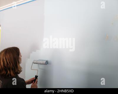 A light blue wall being painted a darker shade of blue Stock Photo
