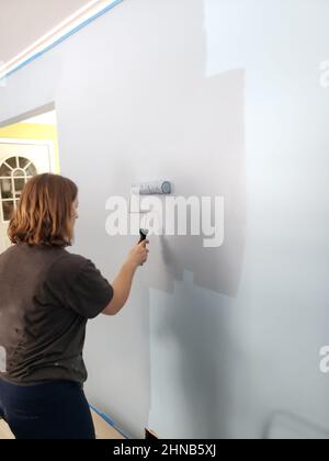A light blue wall being painted a darker shade of blue Stock Photo