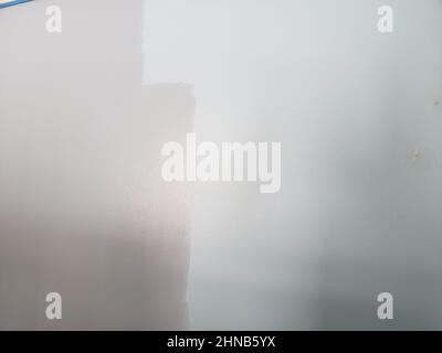 A light blue wall being painted a darker shade of blue Stock Photo