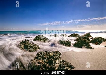 Waves breaking around the exposed rocks of the artificial reef during low tide, at Red Reef Park in Boca Raton Stock Photo