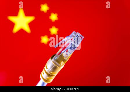 Internet in China concept. Ethernet cable connector and blurred Chinese flag on the background. Selective focus. Stock Photo