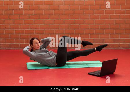 nice middle aged woman doing pilates lessons online on laptop Stock Photo