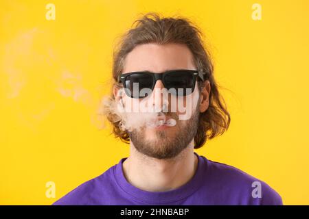Smoking young man on yellow background Stock Photo