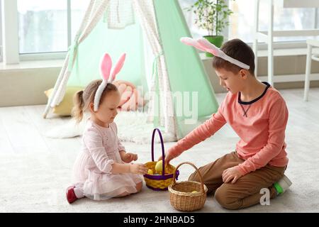 Cute little children and baskets with Easter eggs at home Stock Photo