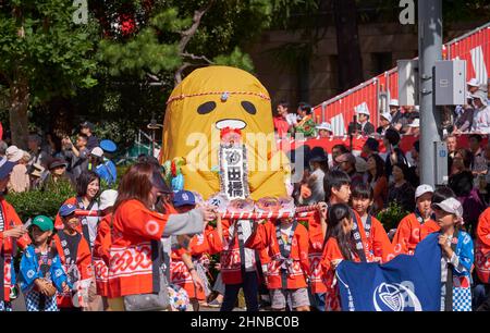 Nagoya, Japan – October 20, 2019: The schoolchildren parade with the funny and original mikoshis with anime figure of Gudetama (lazy egg). Nagoya fest Stock Photo