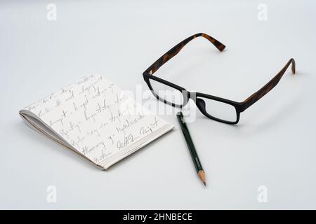 Notebook, glasses, green pencil and white background Stock Photo