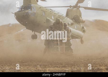 Soldiers assigned to 2nd Battalion, 12th Field Artillery Regiment, 1st Stryker Brigade Combat Team, 4th Infantry Division, hold on to the cargo during a sling load operations training exercise with the Boeing CH-47 Chinook, Feb. 9, 2022, at Fort Carson, Colorado.  The helicopter sling load method of carrying cargo and equipment overcomes many of the obstacles that hinder other modes of movement.    (U.S. Army photos by Scyrrus Corregidor) Stock Photo