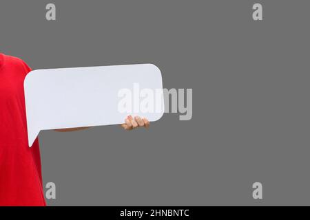 unknown man in red T-shirt holds empty blank white sheet or signboard on gray background Stock Photo