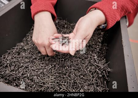 Woman in building materials store buys screws self tapping. Hands close up shot Stock Photo