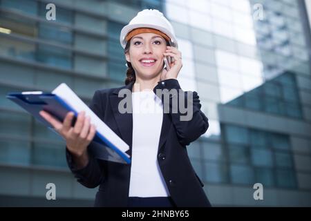 Woman architector in suit and hat is talking about project by the phone Stock Photo