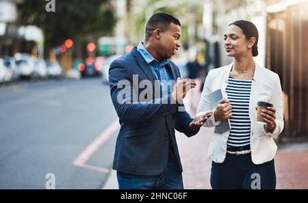 Walking towards their next big opportunity. Shot of two businesspeople having a discussion while walking in the city. Stock Photo