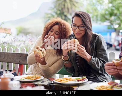 This is the best place in town. Cropped shot of a friends eating burgers outdoors. Stock Photo