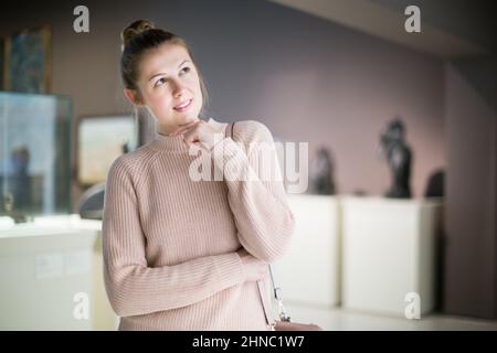 Woman visitor in museum looking at art exposition Stock Photo