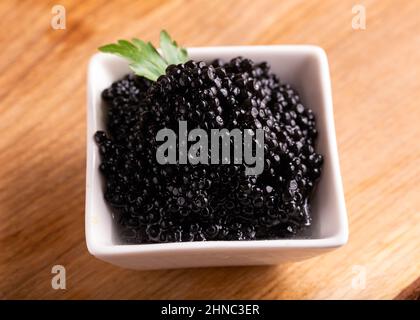 Bowls with black caviar on wooden table Stock Photo