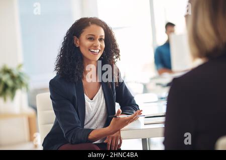 Quick catch up with a coworker. Shot of two young women having a conversation in a modern office. Stock Photo