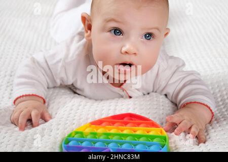 Happy Kid Playing with Pop It. Newborn Baby Playing with Simple Dimple. T Stock Photo