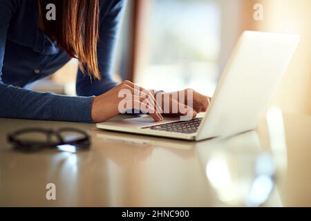 Checking her email at home. Shot of an unidentifiable woman using her laptop while standing in her kitchen. Stock Photo