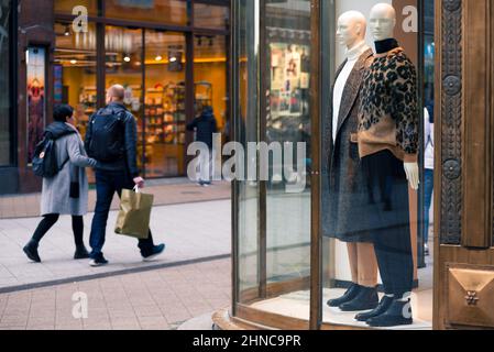Couple passing by mannequins in the glass case Stock Photo