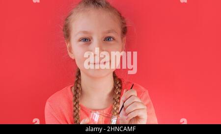 Child eating yogurt jelly pink background. Dairy product diet Lactobacillus Acidophilus, healthy homemade breakfast menu. Kids healthcare. Vegan food Stock Photo