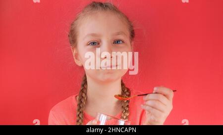 Child eating yogurt jelly pink background. Dairy product diet Lactobacillus Acidophilus, healthy homemade breakfast menu. Kids healthcare. Vegan food Stock Photo