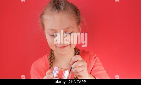 Child eating yogurt jelly pink background. Dairy product diet Lactobacillus Acidophilus, healthy homemade breakfast menu. Kids healthcare. Vegan food Stock Photo