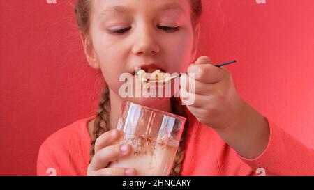 Child eating yogurt jelly pink background. Dairy product diet Lactobacillus Acidophilus, healthy homemade breakfast menu. Kids healthcare. Vegan food Stock Photo