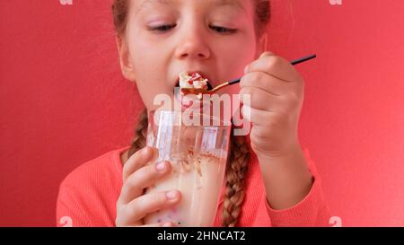 Child eating yogurt jelly pink background. Dairy product diet Lactobacillus Acidophilus, healthy homemade breakfast menu. Kids healthcare. Vegan food Stock Photo