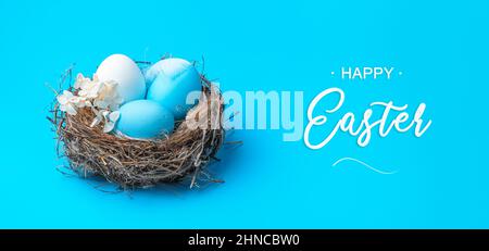 Happy Easter, a nest with Easter eggs on a blue background. Side view. Easter, spring background. Stock Photo